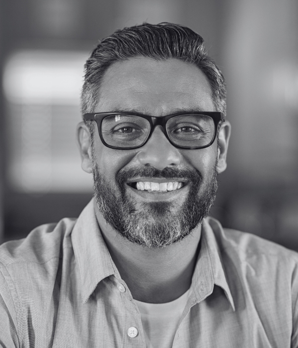 Confident Indian man, with a beard, wearing glasses, smiling at the camera